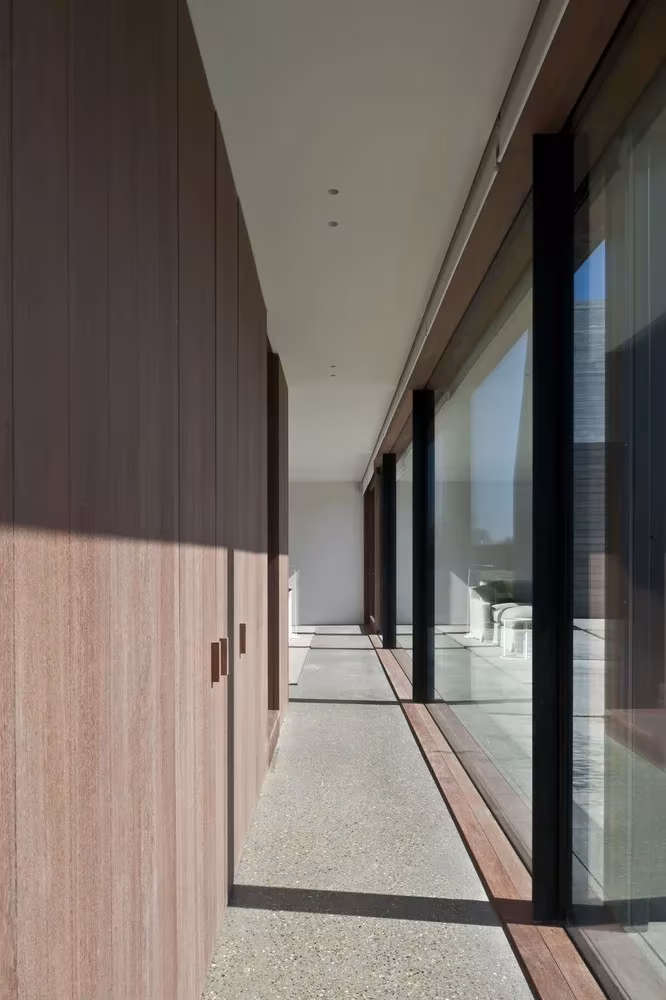 revestimiento interno en madera tostada DCII Ventanales Galería de la Casa DC II entre un panel de madera y el gran ventanal con carpintería negra