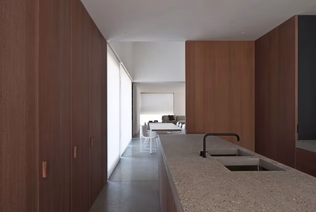 revestimiento interno en madera tostada DCII Cocina de la Casa DC II con isla de piedra, grifo negro y armarios de madera sin tiradores