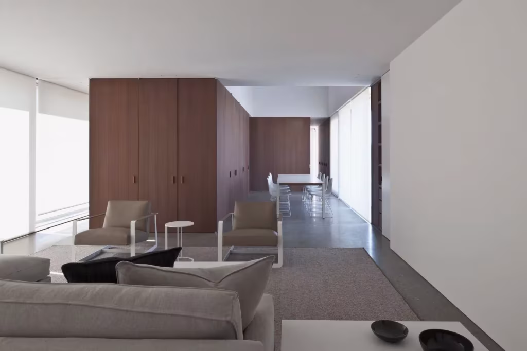 Salón de la Casa DC II con sofás grises, armarios de madera y suelo continuo bajo un techo blanco