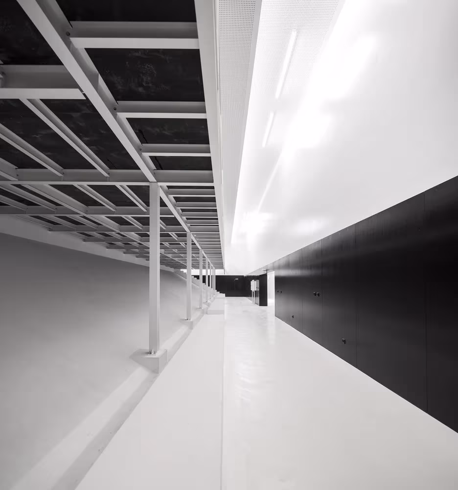 Galería cubierta de la ESTIG de Beja con pérgola de rejilla y paramento negro a lo largo de un pasillo blanco