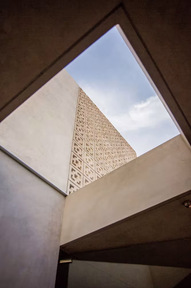 Hueco cenital sobre el patio de la Casa Gabriela con una pared de celosía recortada contra el cielo