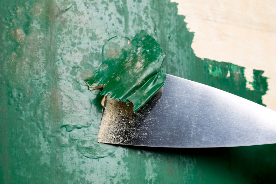 Detalle del decapante retirado con espátula en la restauración de un mueble.