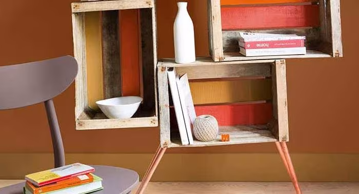 Estantería hecha con cajas de fruta de madera pintadas en rojo y blanco sobre una pared terracota