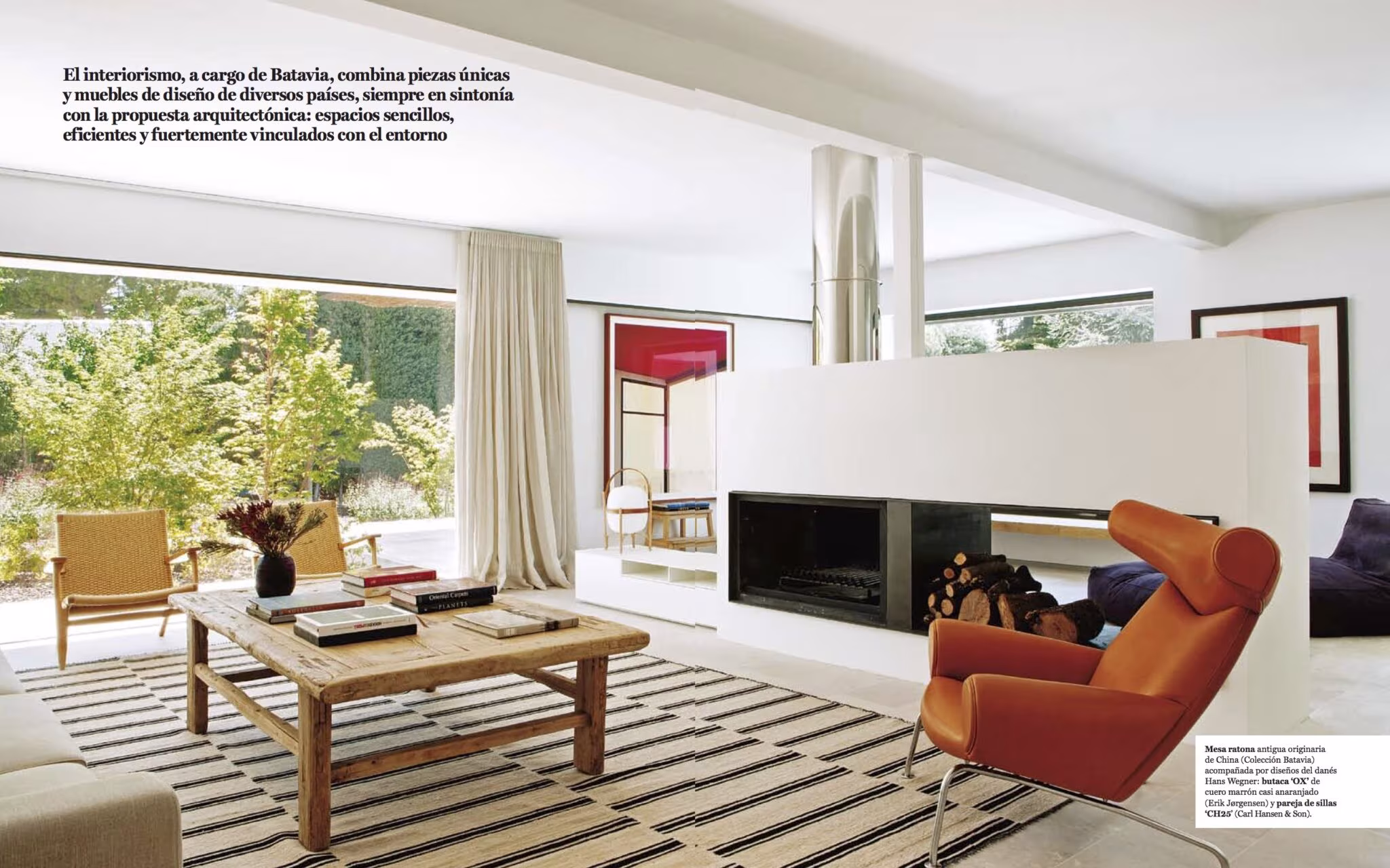 Doble página de Living con el salón de La Moraleja, chimenea bajo un volumen blanco y butaca naranja de BATAVIA