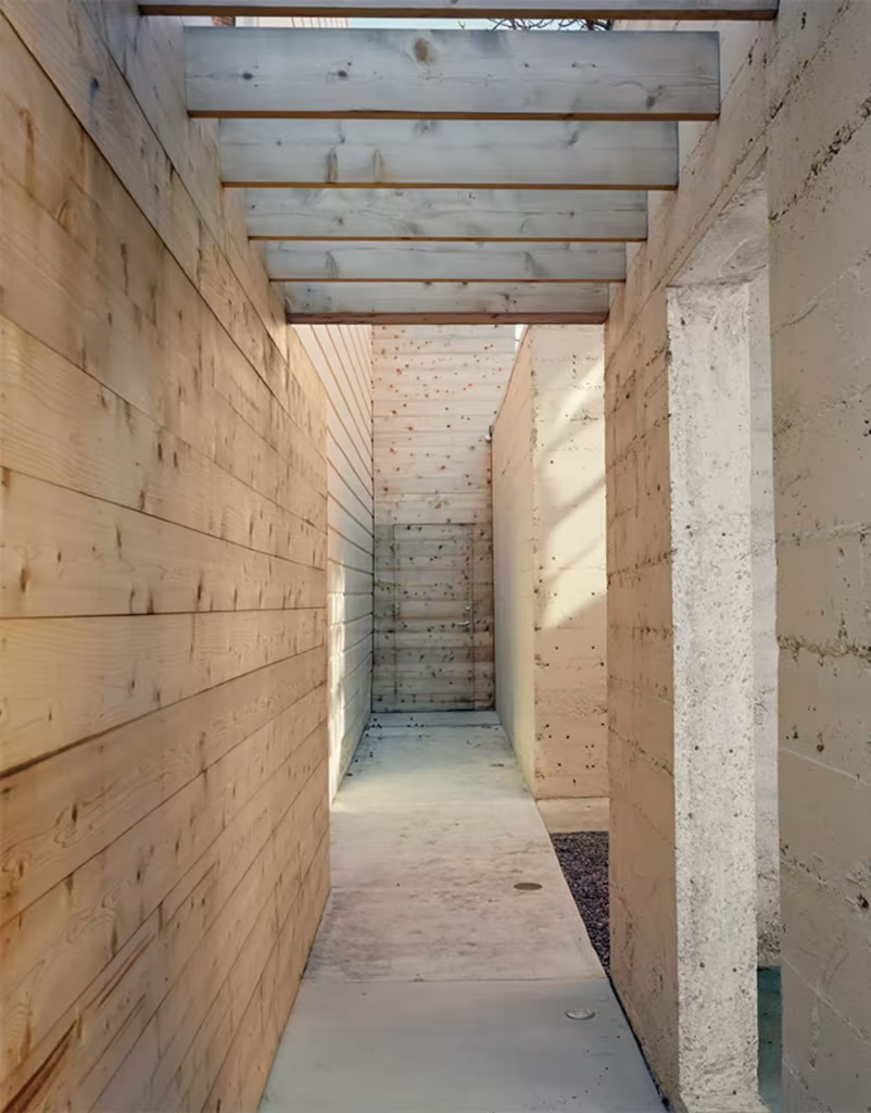 Shotwell Residence de Todd Davis Cedro rojo, materiales Pasillo exterior entre muros de tablas de madera y hormigón bajo una pérgola de vigas, en la Shotwell Residence