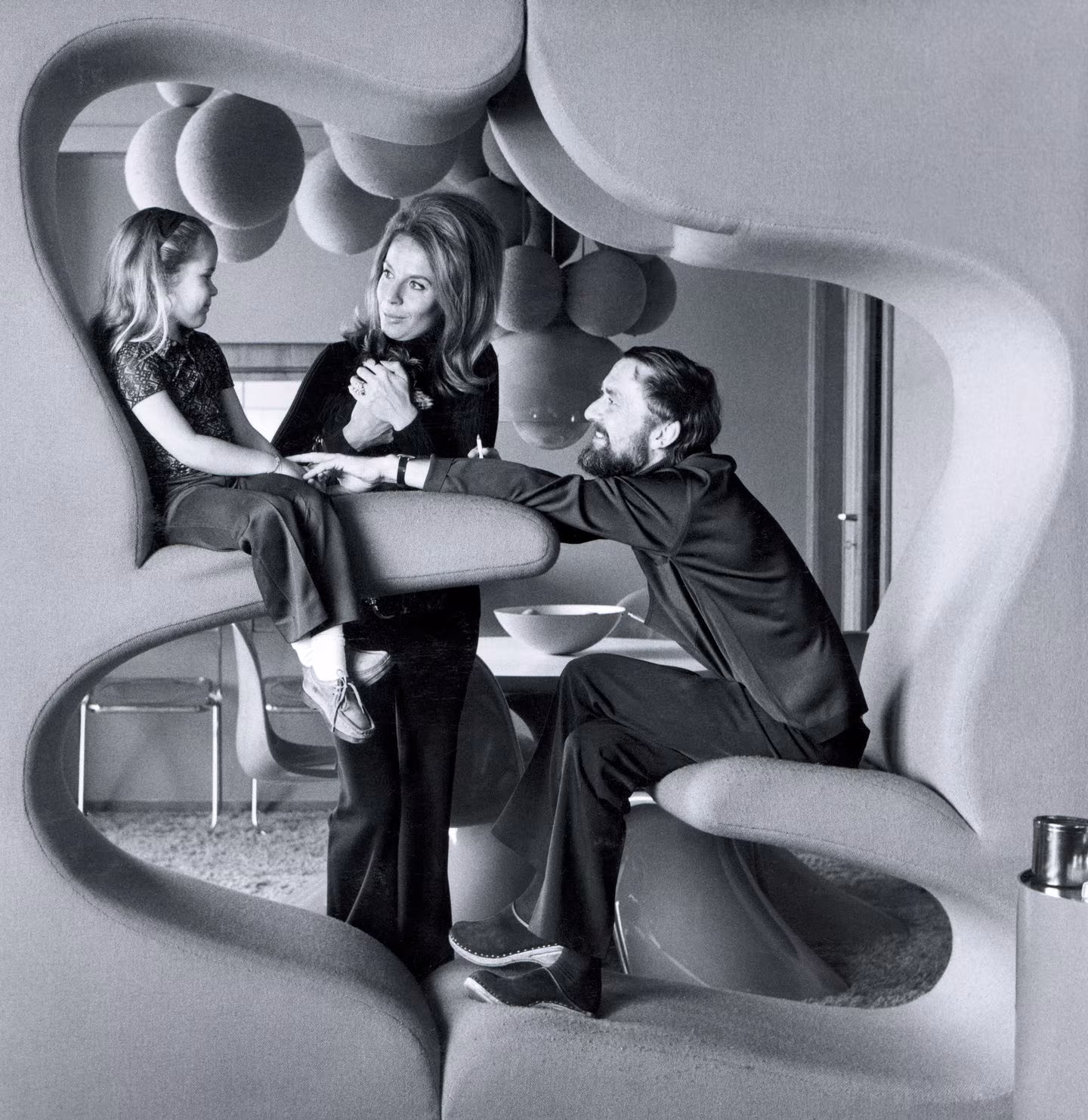 Familia sentada en el mueble Living Tower de Verner Panton, de formas curvas tapizadas, en blanco y negro