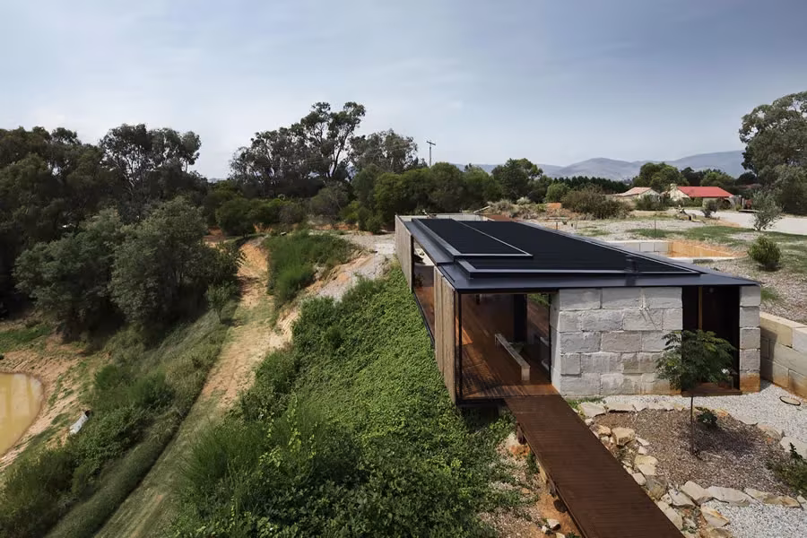Vista aérea de la Sawmill House sobre el borde de una antigua cantera, con muro de bloques y cubierta oscura