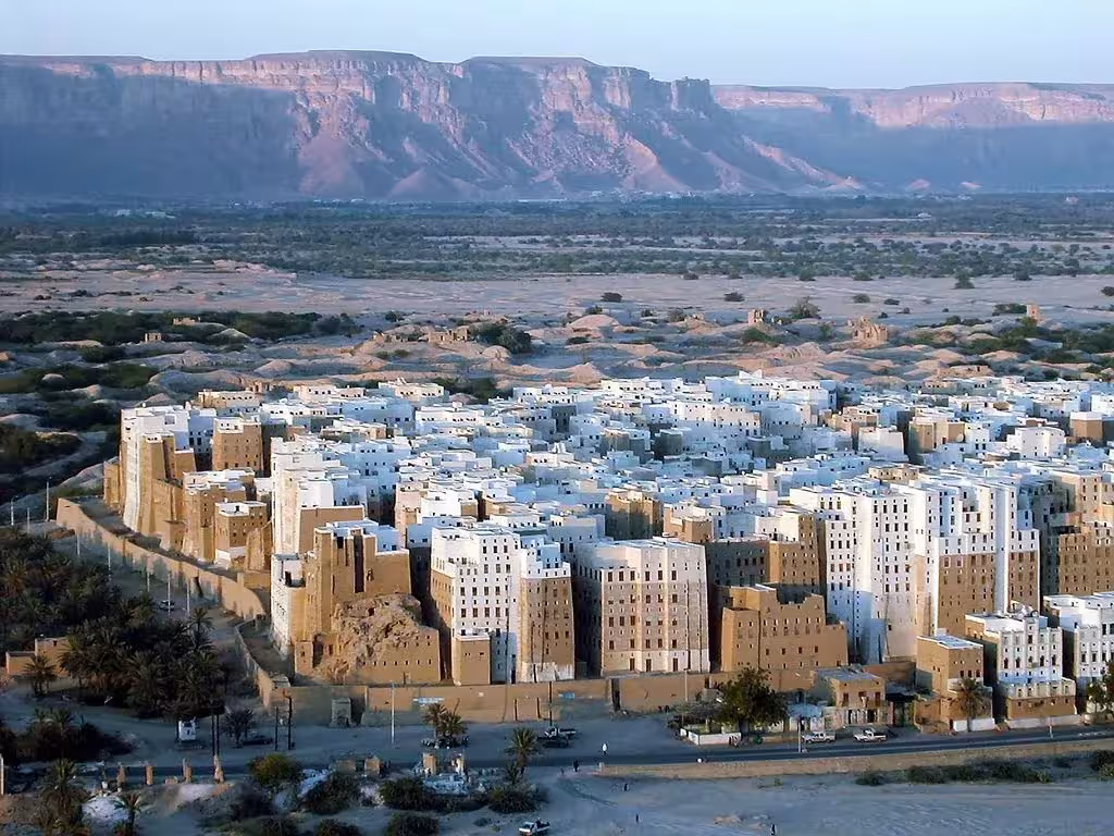 Shibam al amanecer, con sus torres de adobe blancas y ocres y el acantilado al fondo, en Yemen