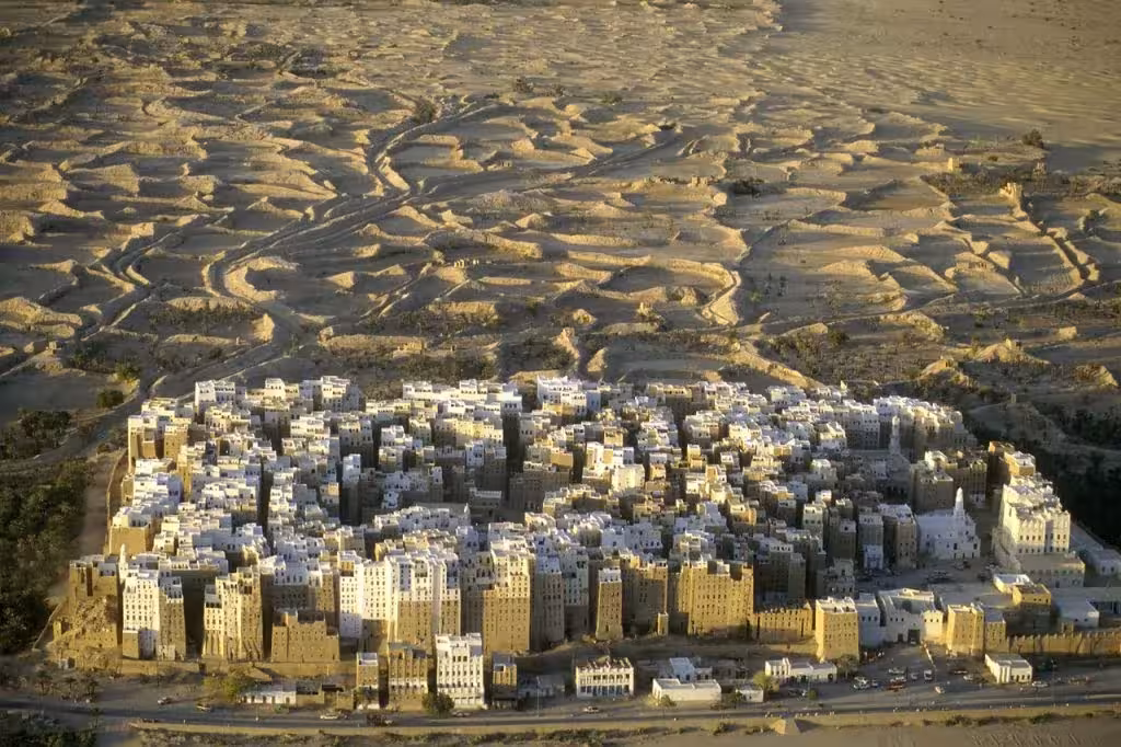 Torres de adobe de Shibam agrupadas en un conjunto compacto sobre un llano de dunas, en Yemen