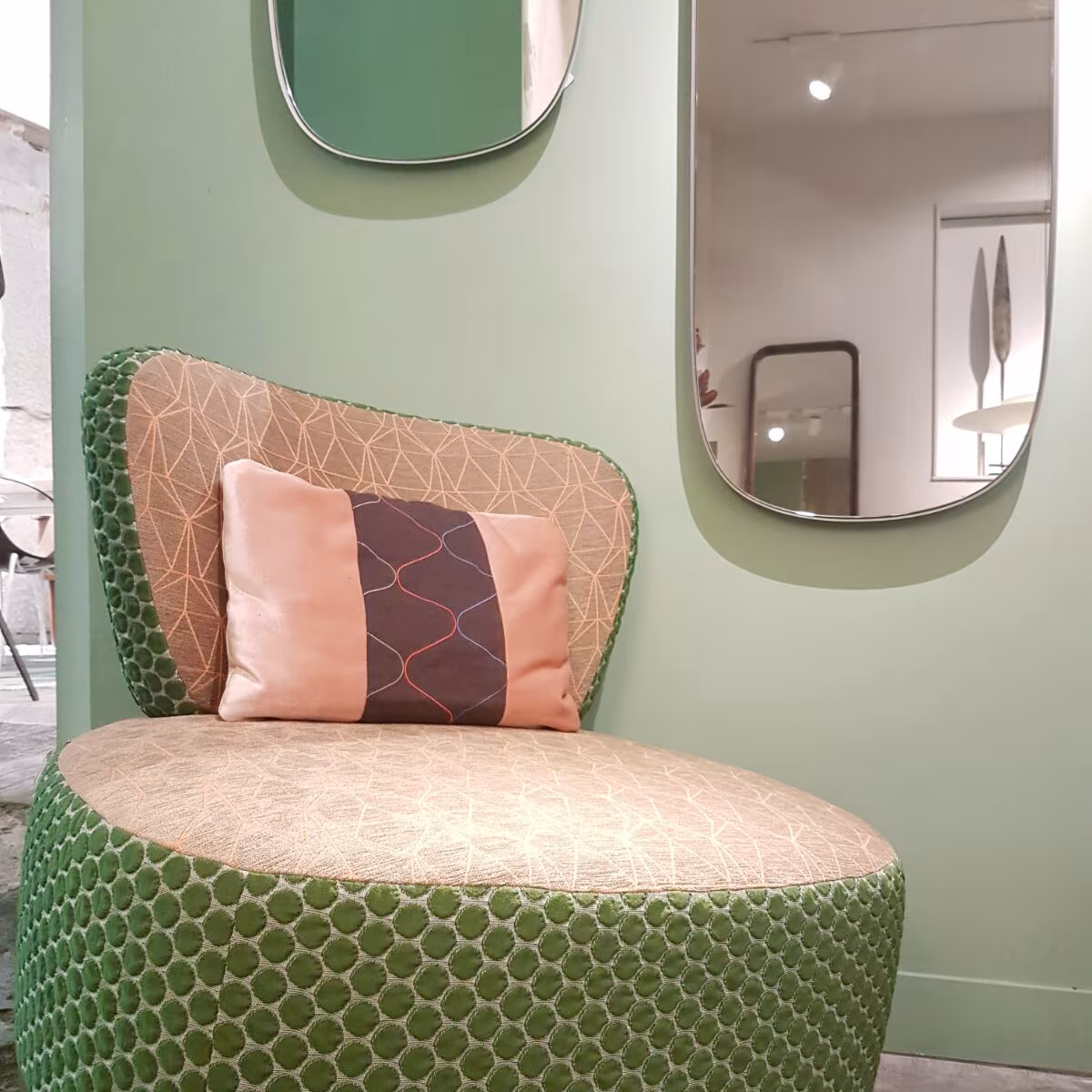 Butaca Sushi de Moroso con tapizados estampados en verde y rosa junto a espejos de formas orgánicas