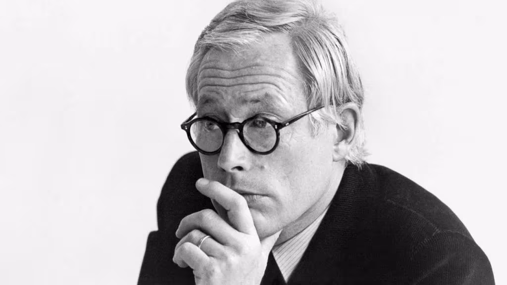Retrato en blanco y negro del diseñador Dieter Rams con gafas redondas y la mano en la barbilla