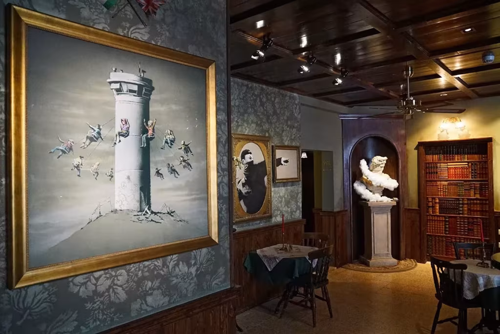 Cuadro de una torre de vigilancia con niños columpiándose en el salón del Walled Off Hotel de Banksy en Belén