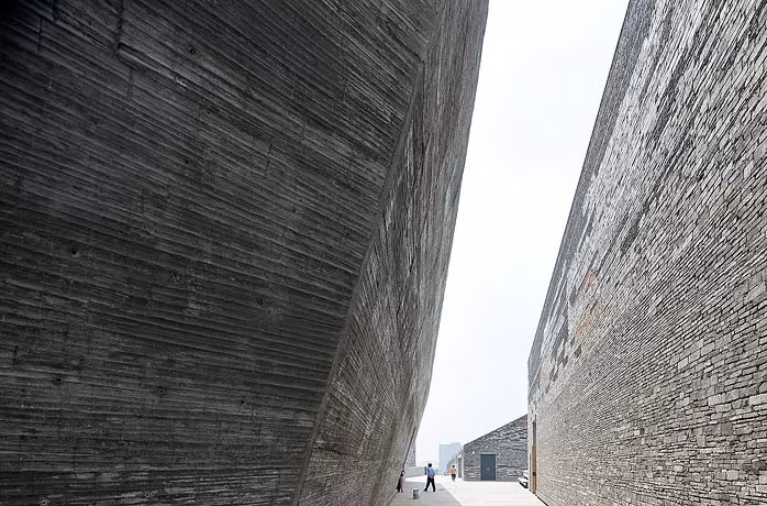 Callejón entre los muros inclinados del Museo de Ningbo, de textura de hormigón encofrado con listones