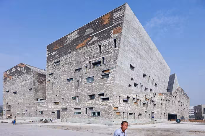 Fachada del Museo de Ningbo con ventanas de tamaños variados y paños de ladrillo reciclado en tonos rojizos