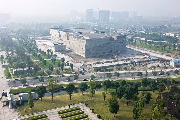Vista aérea del Museo de Ningbo de Wang Shu como una masa pétrea entre parques y avenidas