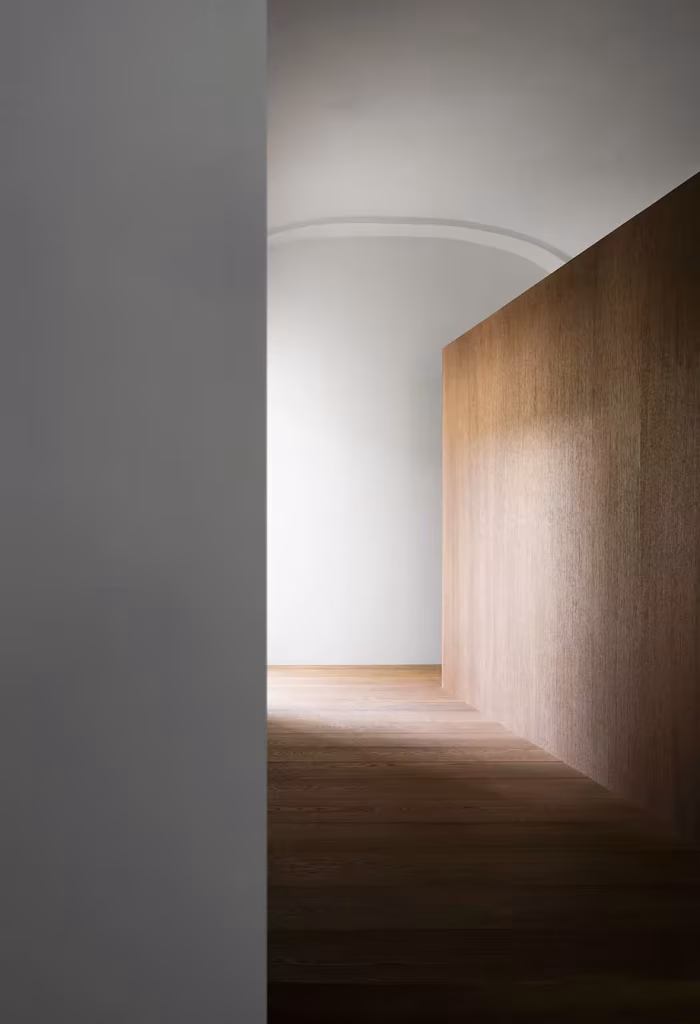 Volumen revestido de madera dentro de una estancia blanca de la Casa AG, con suelo de tarima