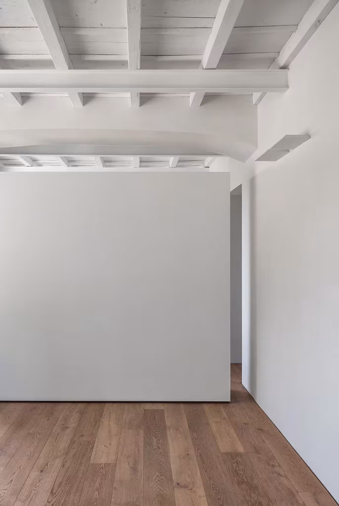 Estancia de la Casa AG con techo de vigas pintadas de blanco, tabique exento y suelo de roble