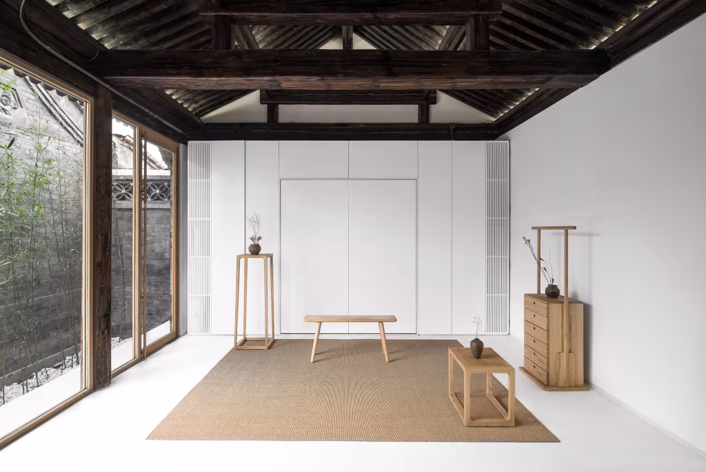 Sala de té blanca de la Twisting Courtyard House con techo de madera tradicional, estera y mesa baja