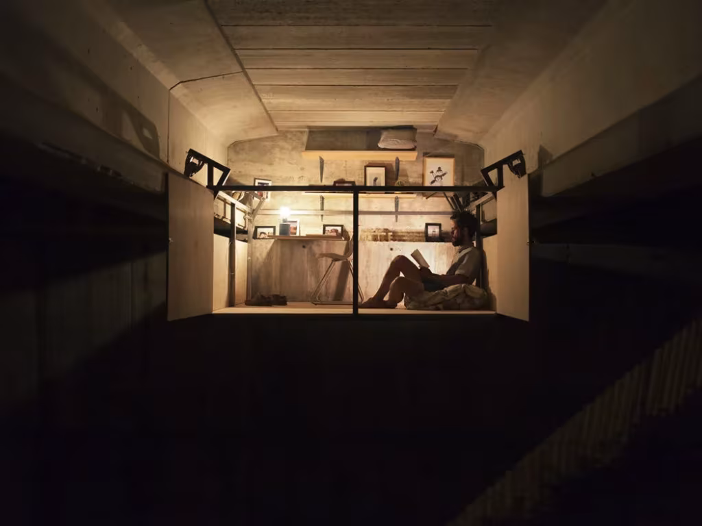 Interior iluminado del estudio de Fernando Abellanas colgado entre las vigas del puente por la noche