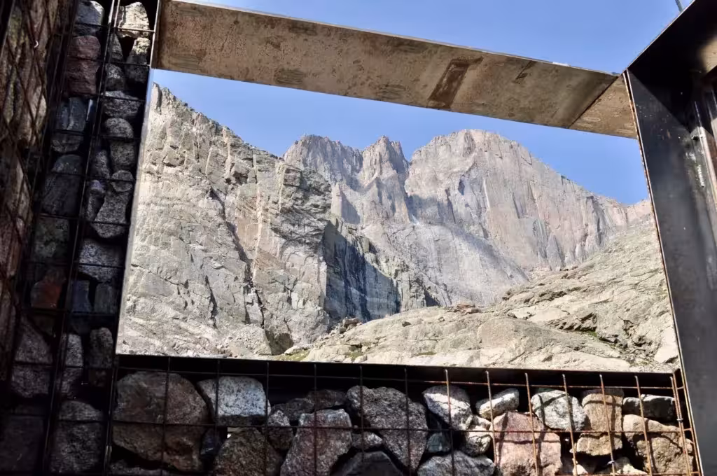 Marco de acero que enmarca las montañas del Longs Peak desde el interior de un aseo con muros de gaviones, Colorado