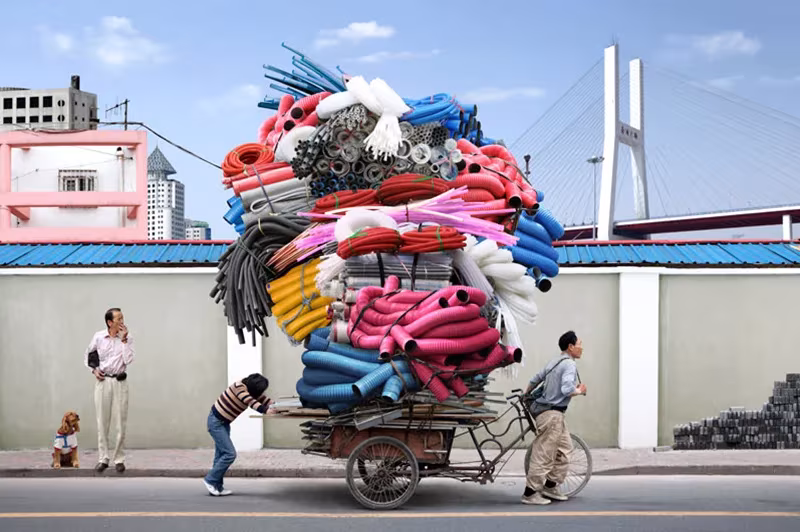Bicicleta de carga con un gran fardo de tejidos de colores junto a un puente atirantado