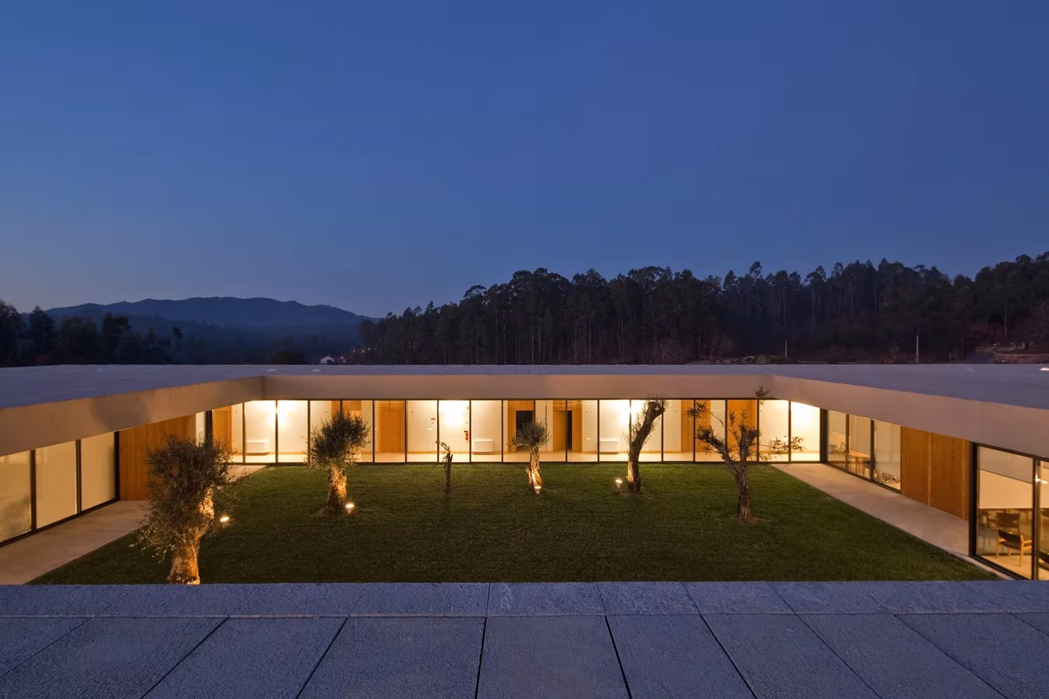 Galerías de la Casa de Magalhães iluminadas alrededor del patio con olivos y los montes al fondo