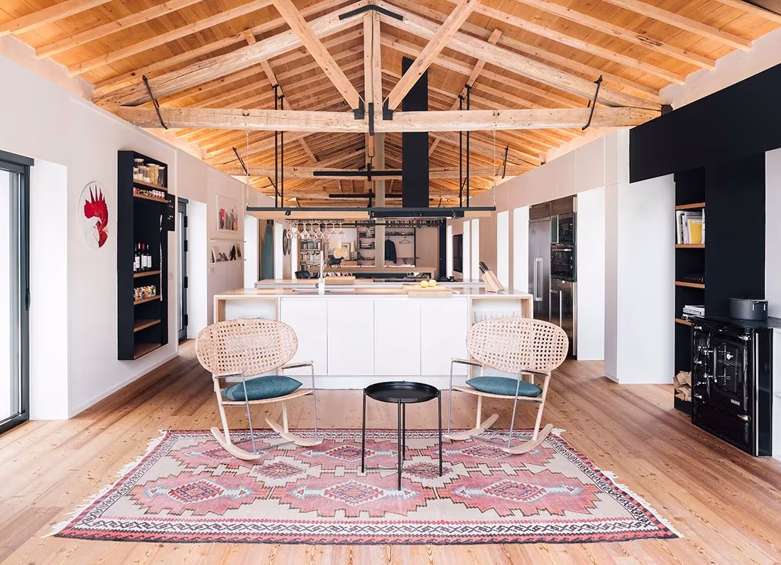 Salón diáfano bajo cubierta de madera a dos aguas, con la cocina al fondo, en la casa de Zooco en Güemes