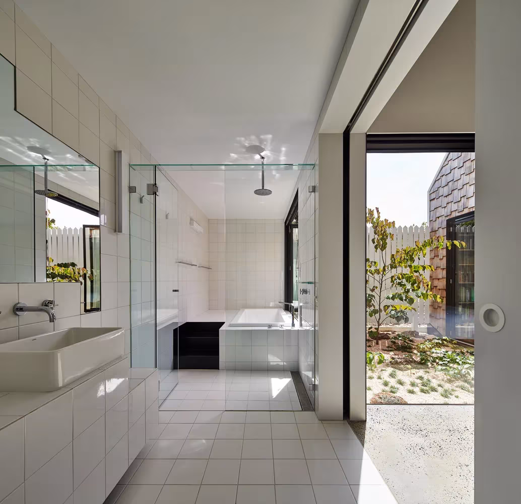 Baño de azulejo blanco con ducha acristalada y puerta corredera abierta al jardín en la Tower House