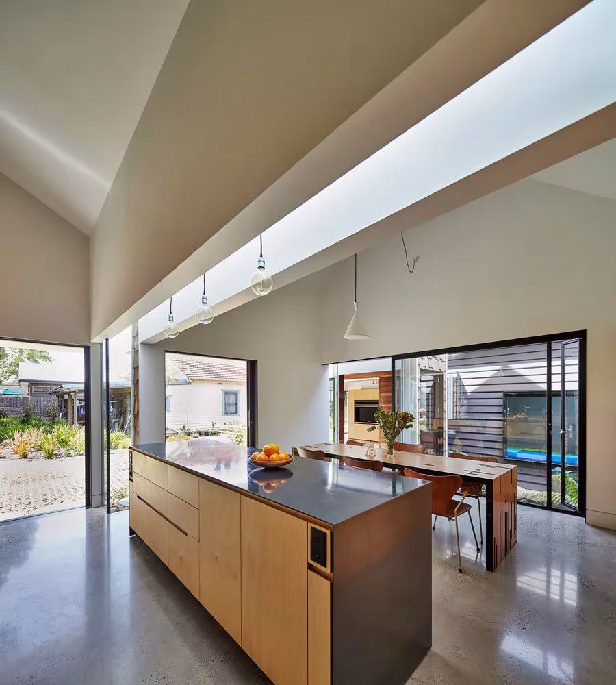 Cocina con isla de contrachapado bajo techo a dos aguas y luz cenital en la Tower House de Melbourne