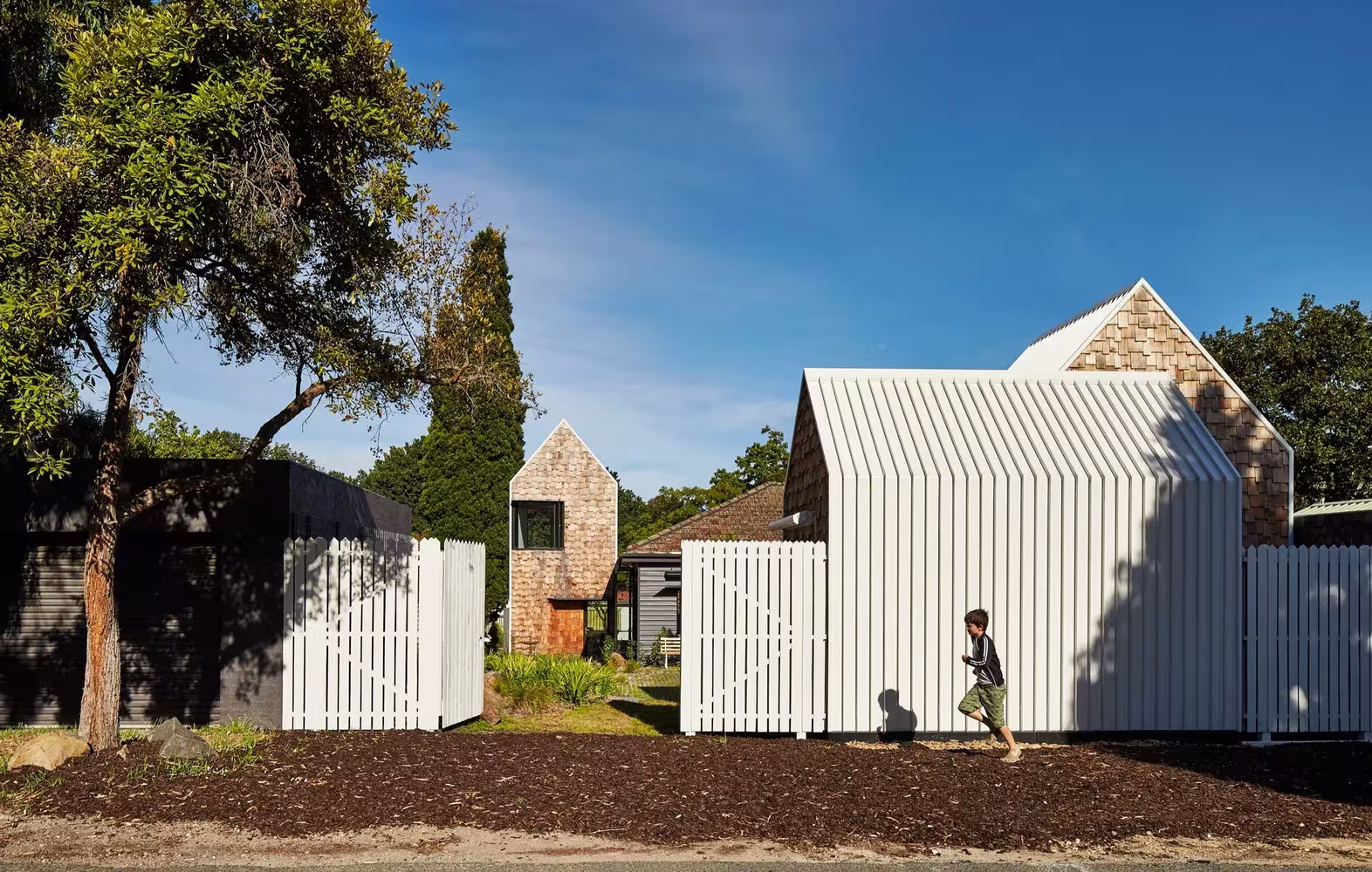 Volumen blanco de listones y cierre de madera junto a la calle en la Tower House de Austin Maynard Architects