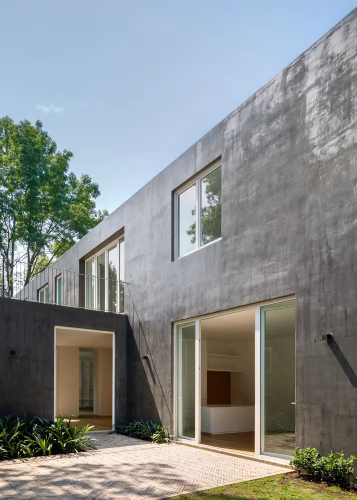 Fachada de hormigón oscuro con ventanas al jardín en la Casa Campestre de DCPP Arquitectos, San Ángel