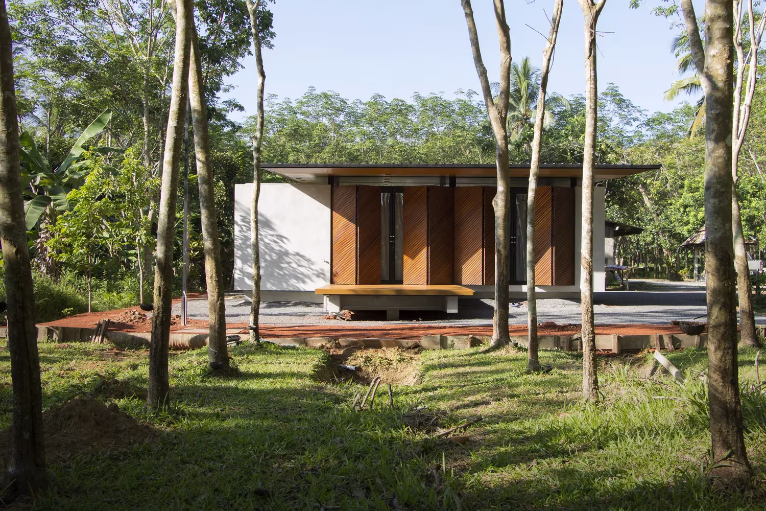 Casa de cubierta plana entre plantaciones de caucho vista desde el claro del bosque, Phatthalung House