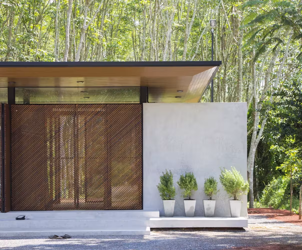 Fachada de lamas de madera en diagonal y macetas de aromáticas junto al muro blanco de la Phatthalung House