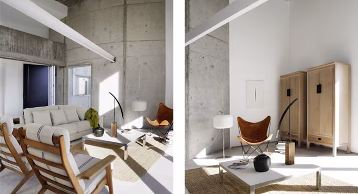 Loft del proyecto RN con hormigón visto, butacas de madera y sofá claro, y un rincón con armario oriental