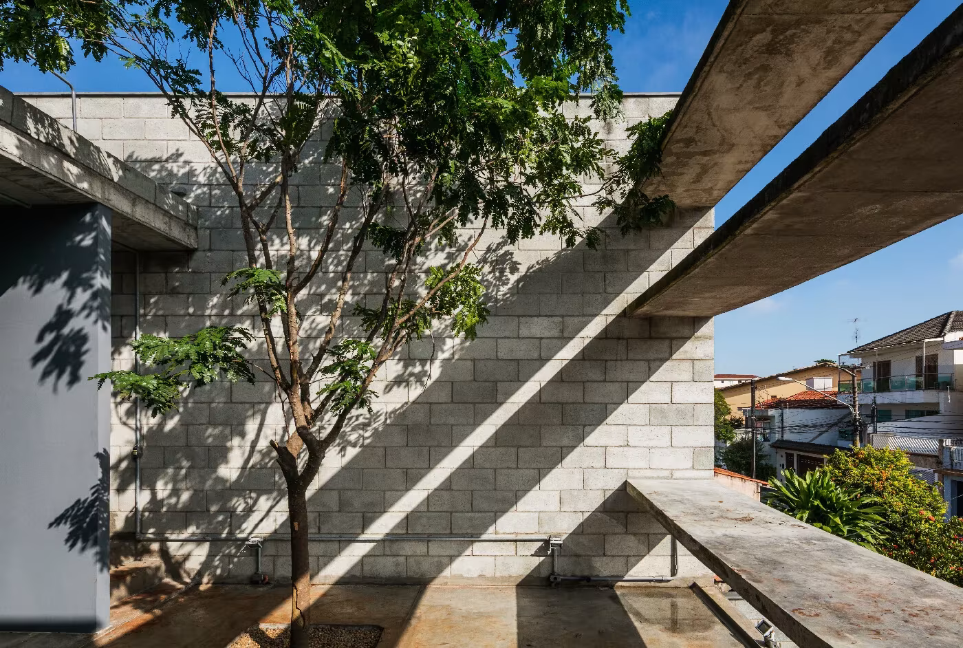 Muro de bloque de hormigón con un árbol y una rampa inclinada de hormigón en una casa de Terra e Tuma, São Paulo