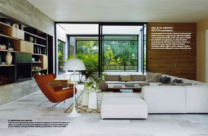 Doble página de Nuevo Estilo con el salón de hormigón visto, librería de madera y gran ventanal sobre el jardín