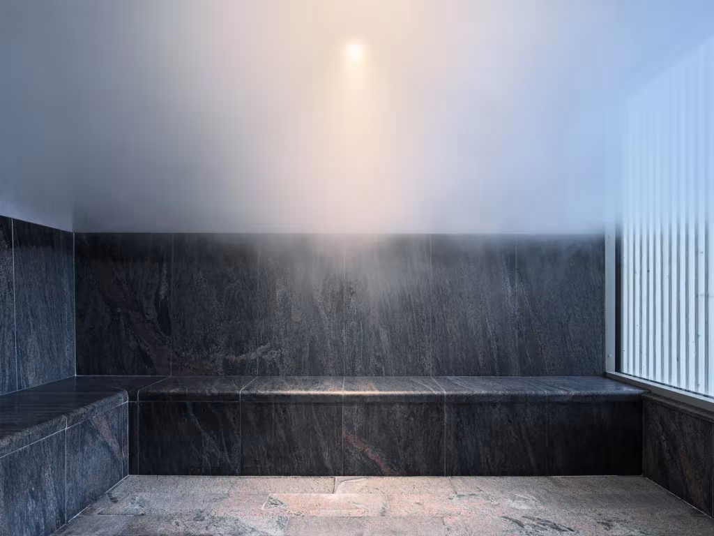 Sala de vapor del Andrum Spa en Suecia con banco y paredes de piedra oscura bajo una luz difusa