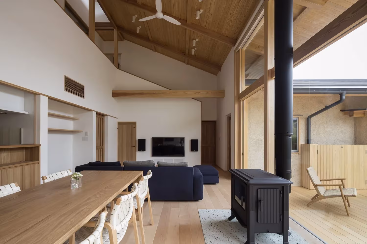 Salón-comedor de doble altura con estufa y cubierta de madera en la Casa Hiiragi de Takashi Okuno