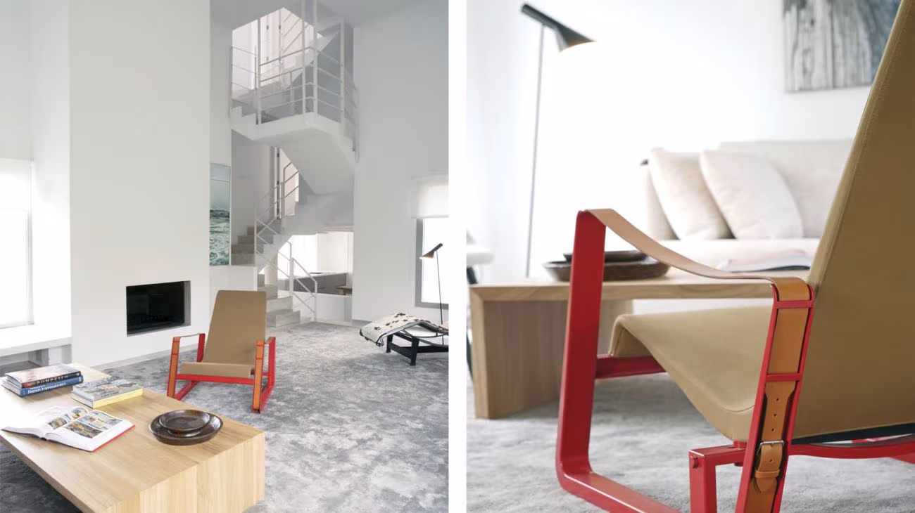 Rincón de estar con butaca de madera y asiento rojo y chimenea blanca junto a una escalera de caracol en un dúplex