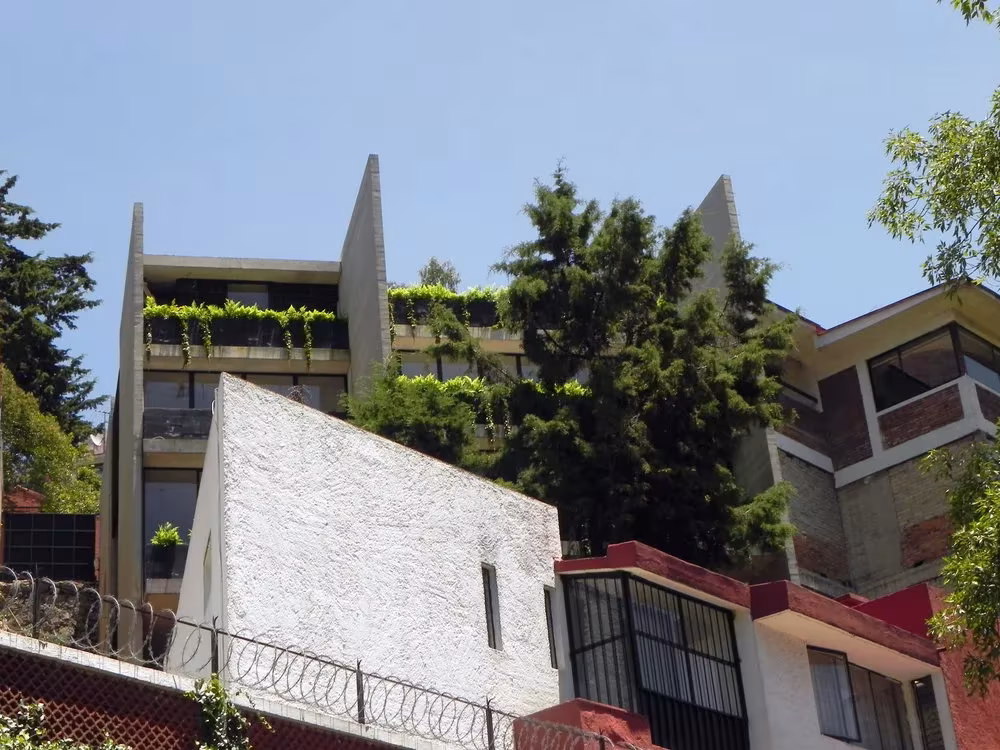 Casa BC de 3ARCH escalonada en la ladera, con muros de hormigón y terrazas con vegetación entre viviendas vecinas