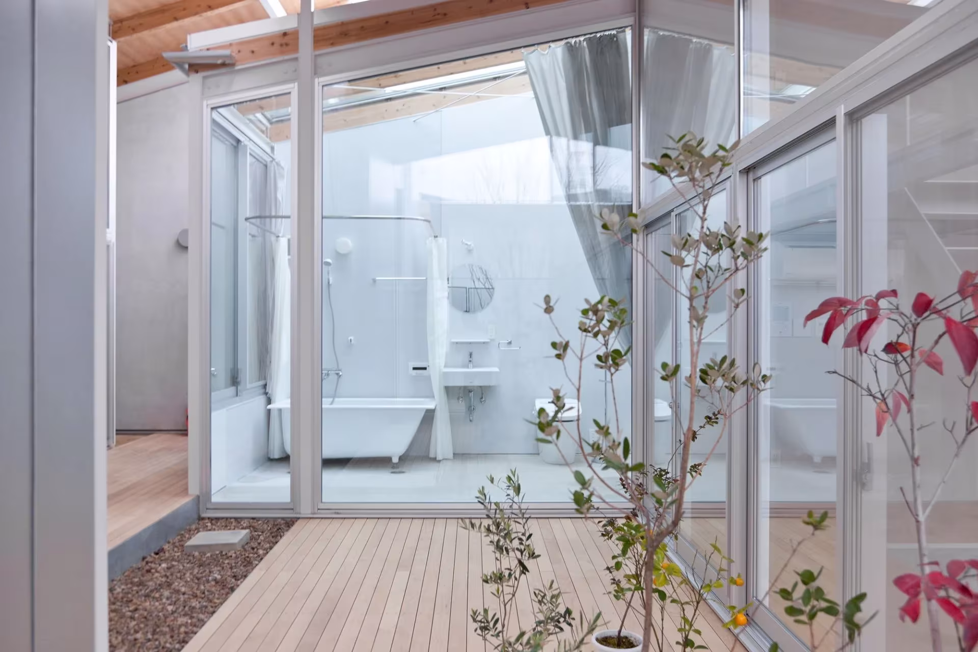 Baño abierto a un patio con tarima de madera y vegetación en la Nishinoyama House de SANAA, Kioto