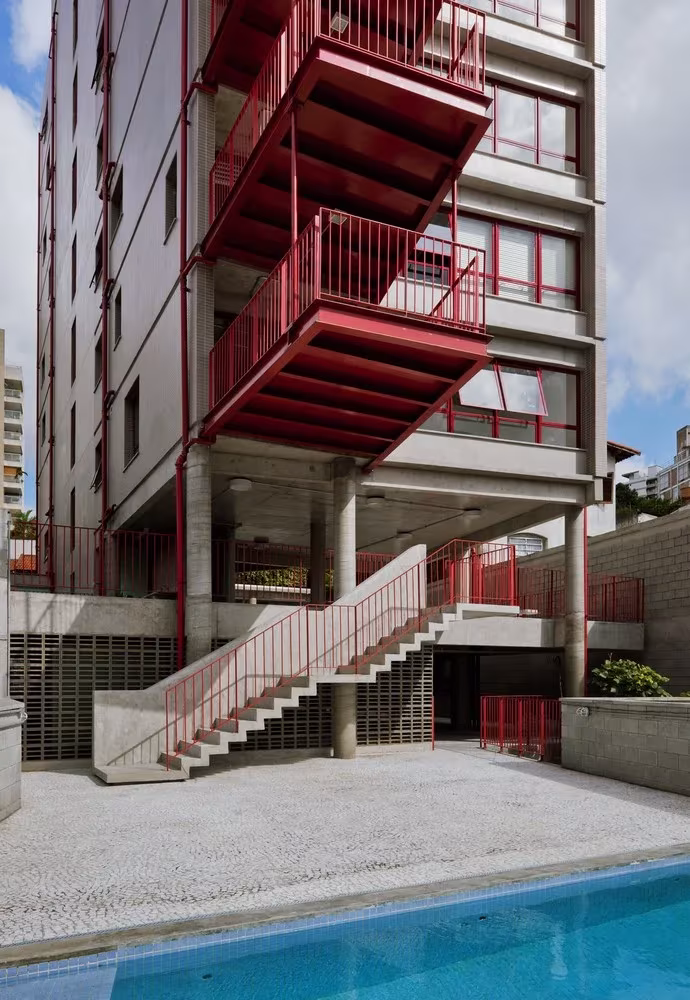 Escalera exterior de hormigón y balcones rojos junto a la piscina en el edificio de Grupo SP en São Paulo