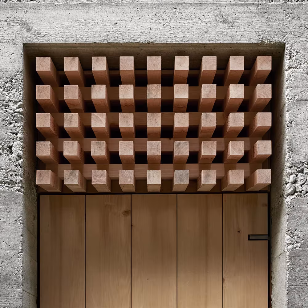 Puerta de la capilla de Wirmboden bajo un dintel de rejilla de tacos de madera encajado en el hormigón