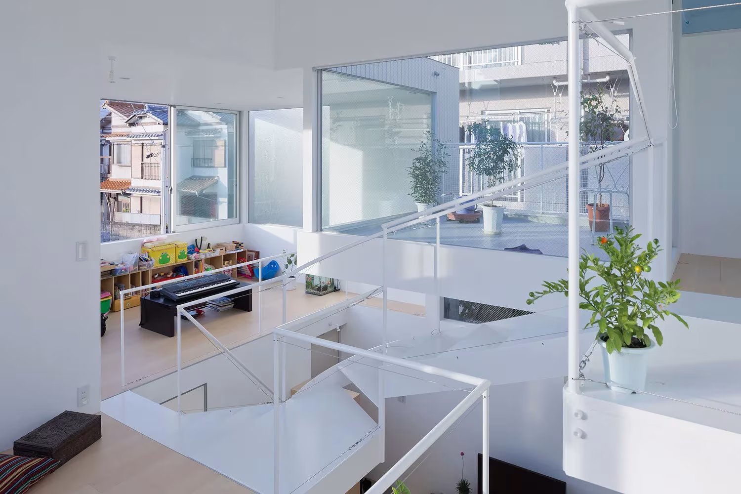 Salón de la Casa Chayagasaka con plantas, barandillas blancas y ventanas a la ciudad de Nagoya, Tetsuo Kondo