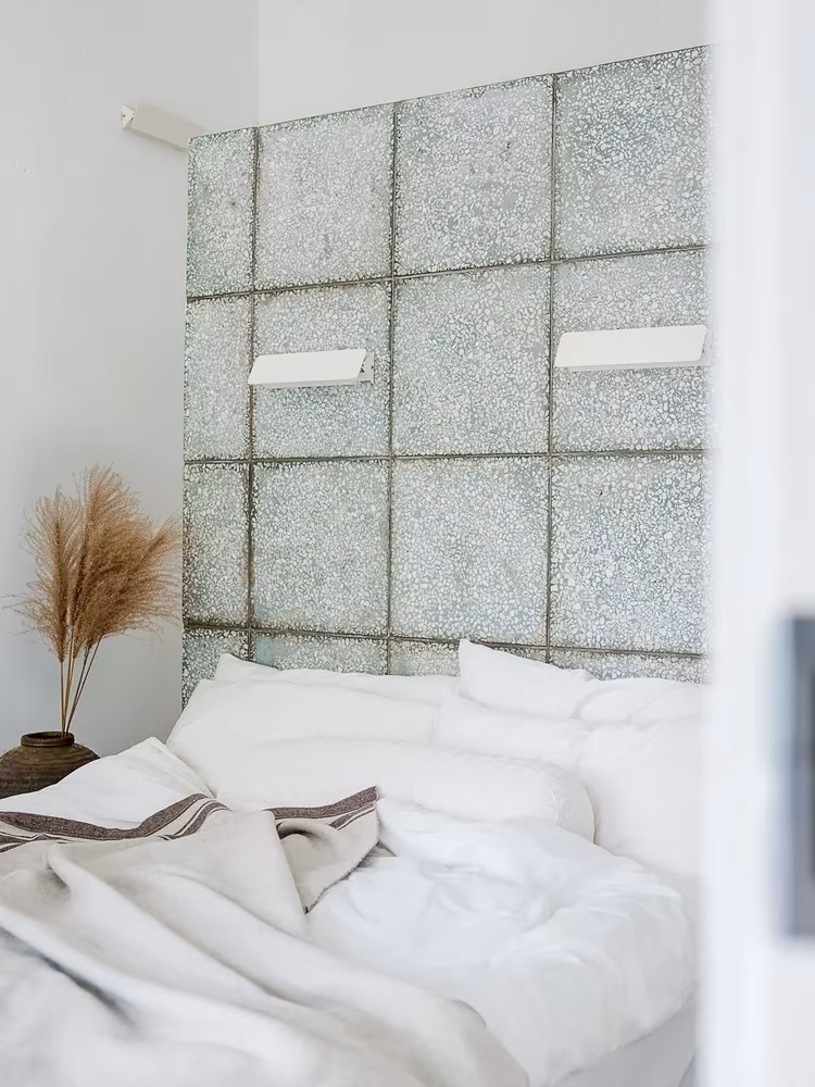 Dormitorio blanco con cabecero de paneles de piedra moteada en el Studio Cottage de Christian Taeubert y Sun Min
