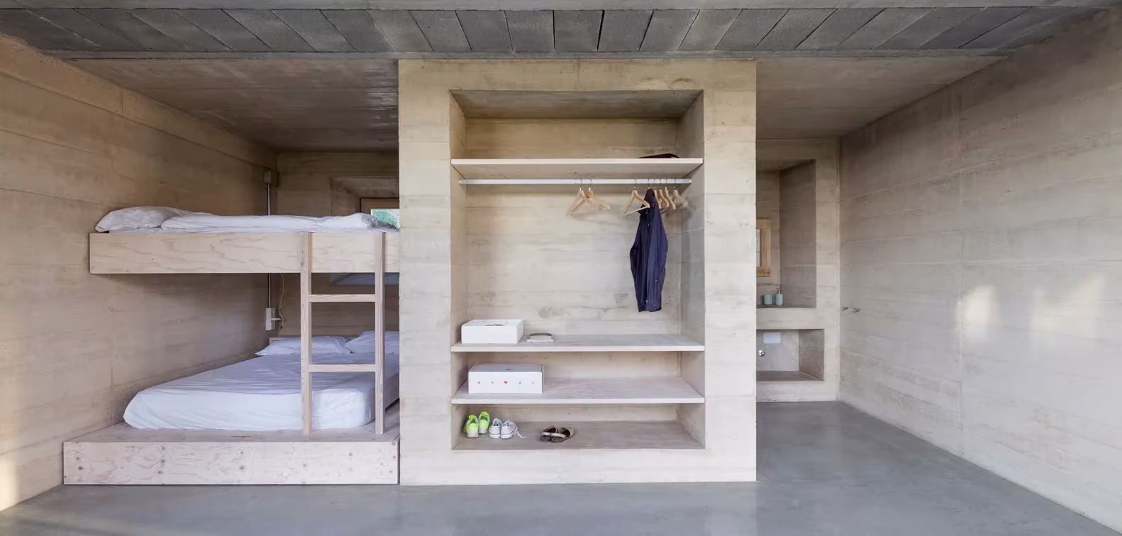 Dormitorio infantil con literas de madera y armario de hormigón visto en la Casa 1413 de H Arquitectes