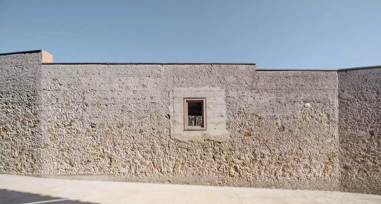 Muro de mampostería con ventana cuadrada y coronación escalonada de la Casa 1413 de H Arquitectes en Ullastret