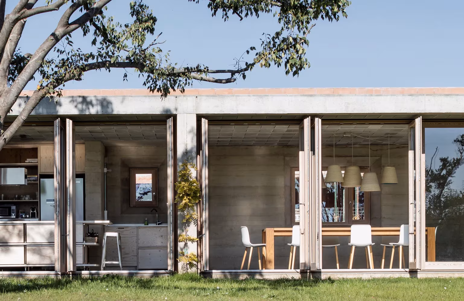 Comedor de la Casa 1413 abierto al jardín con grandes carpinterías de madera, H Arquitectes, Ullastret