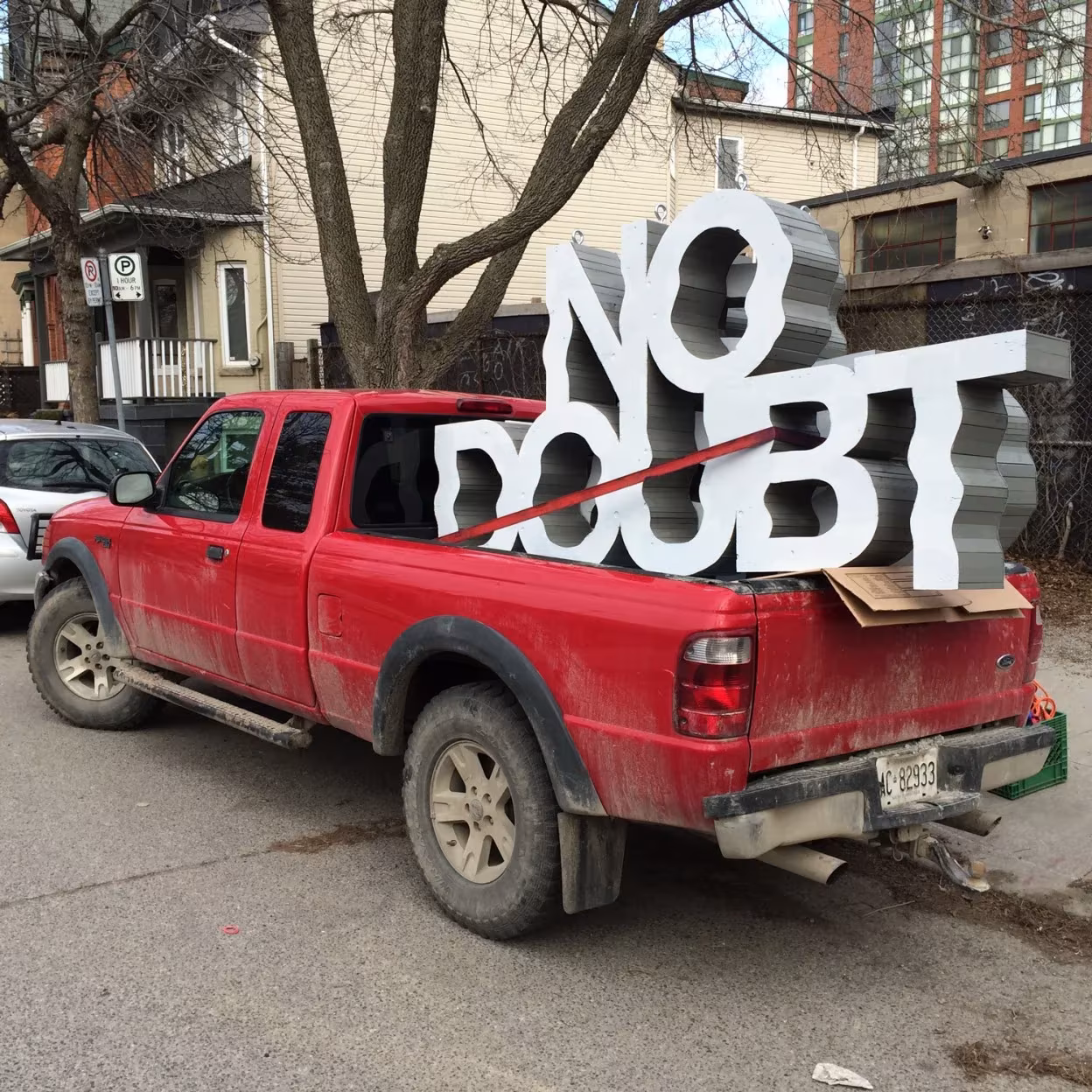 Escultura de letras blancas onduladas «No Doubt» de Wheatley y Dean sobre la caja de una camioneta roja