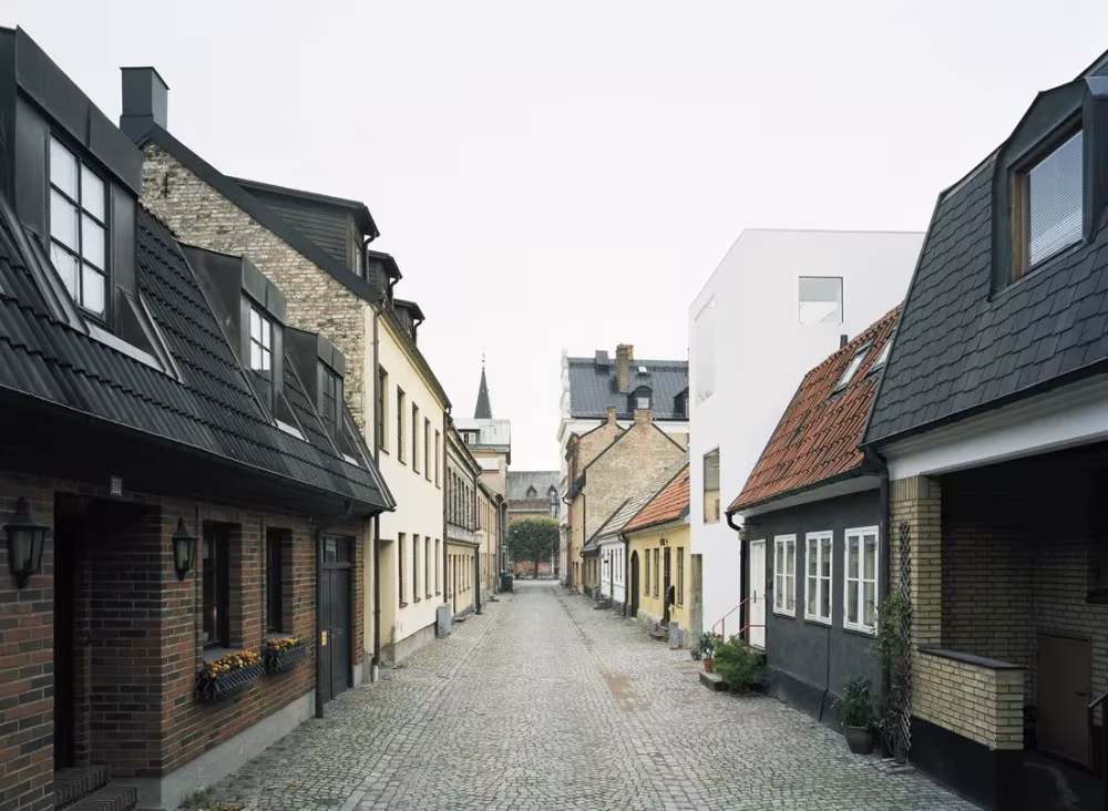 Calle adoquinada de Landskrona con la Townhouse blanca de Elding Oscarson entre casas tradicionales de tejado inclinado